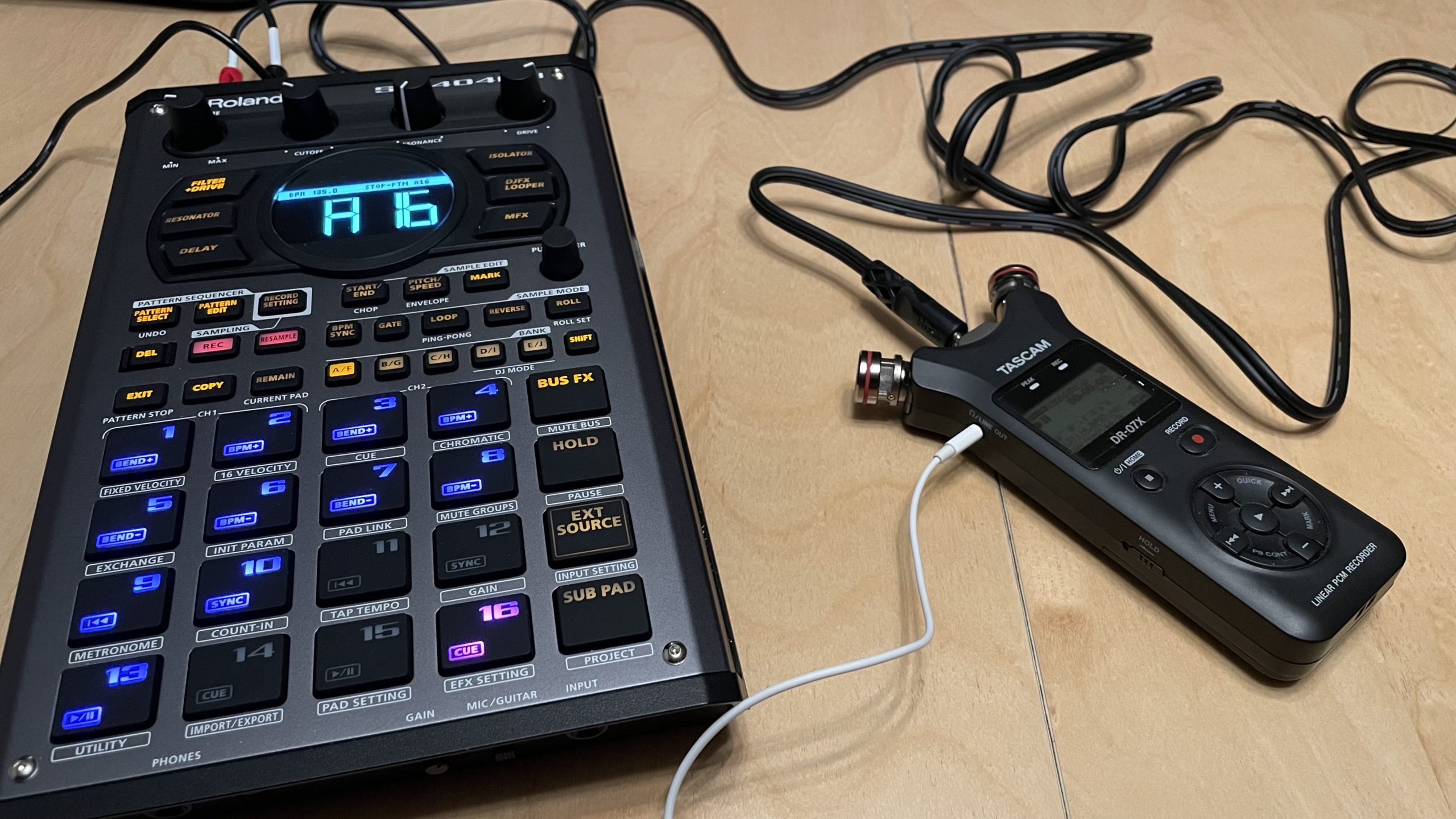 A Roland SP404 mk2 connected to a small Tascam recorder sitting on a table